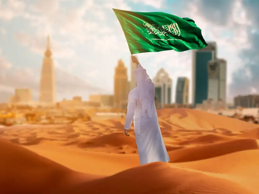 رجل يلوح بالعلم السعودي في اليوم الوطني